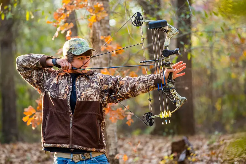 Bow shooting a compound bow in woods