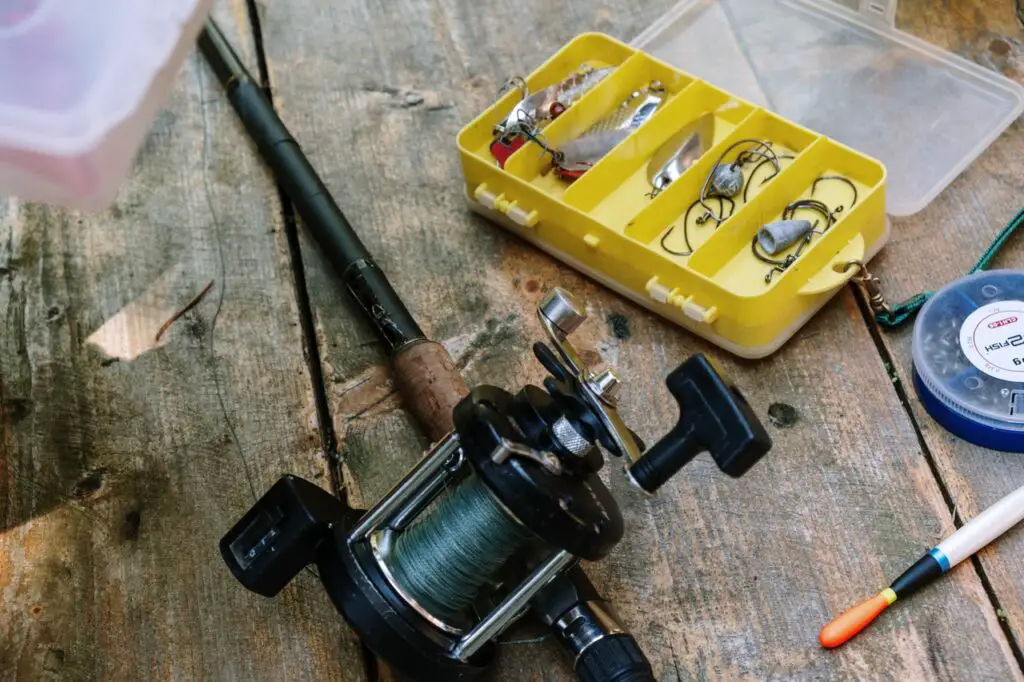 Fishing rod with spinning reel and fishing lures on a wooden table