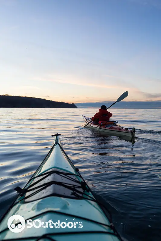 Adventurous man kayaking on the sea during a vibrant and colorful winter sunset