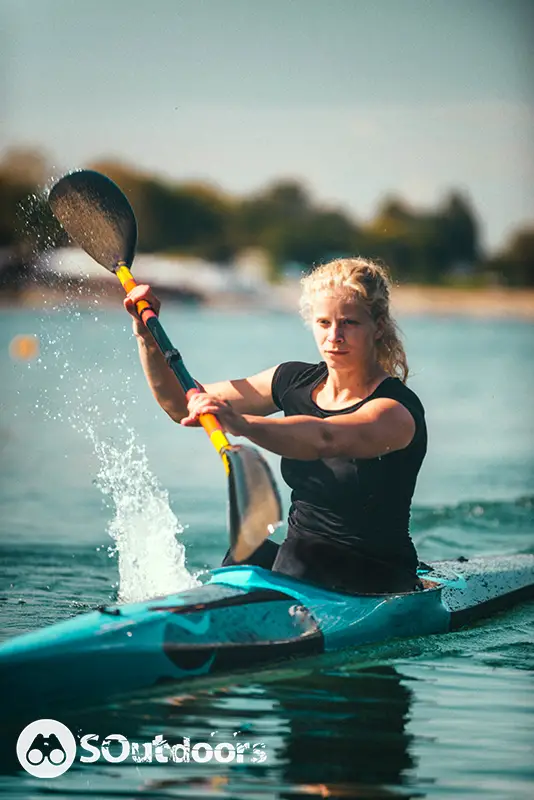 Female kayaker training on lake using a sit-inside kayak