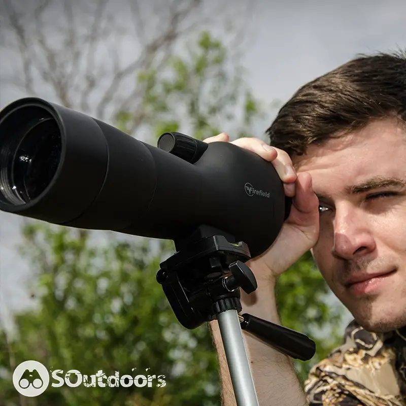 A young man looking straight through a spotting scope