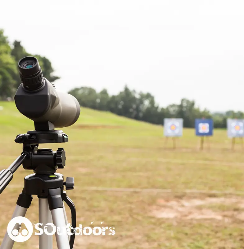 Spotting scope on tripod at outdoor archery target range with three boards