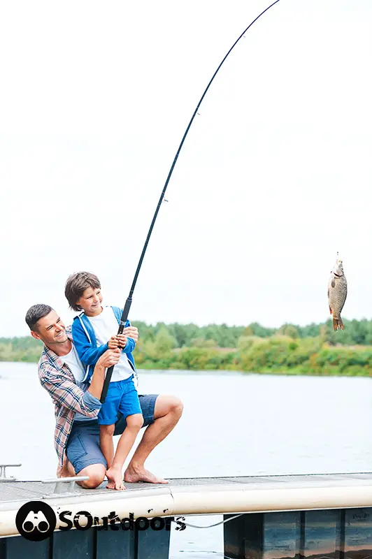 Father and son stretching a fishing rod with fish on the hook