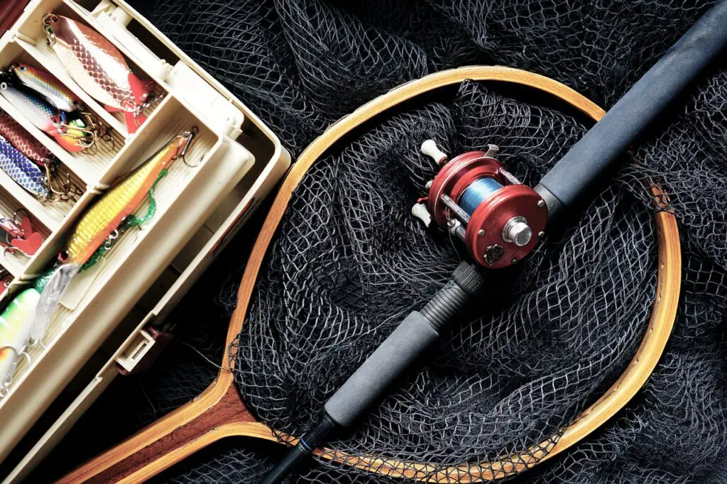 Fishing rod over a black net with a box of fishing lures