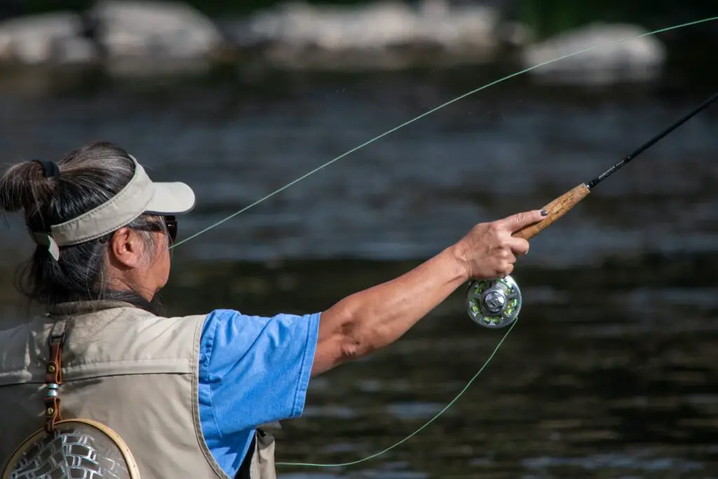 A fisherman casting his fishing rod with fly fishing reels