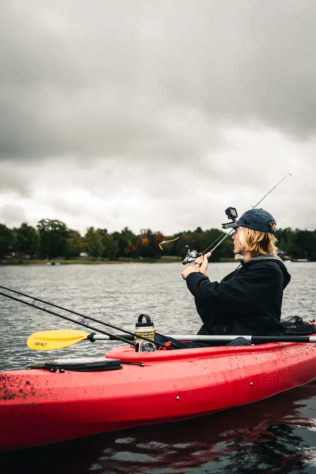 A man on his kayak holding a fishing rod with a fishing lure
